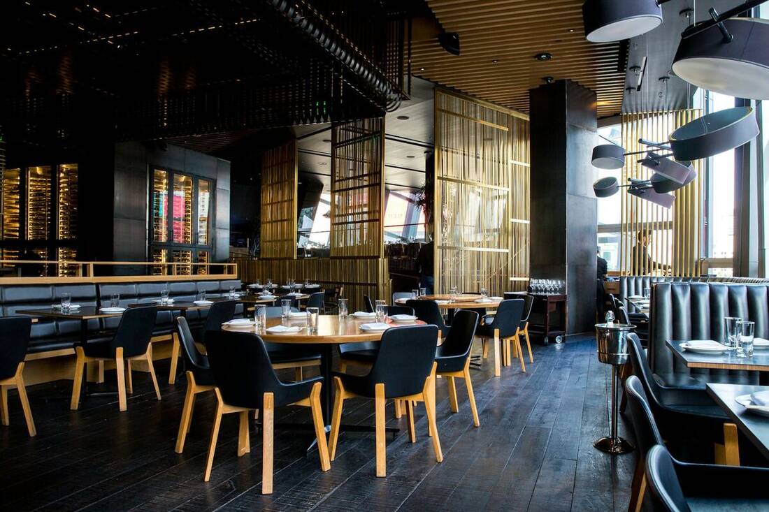 Salle de restaurant chaleureuse à la lumière tamisée, tables dressées