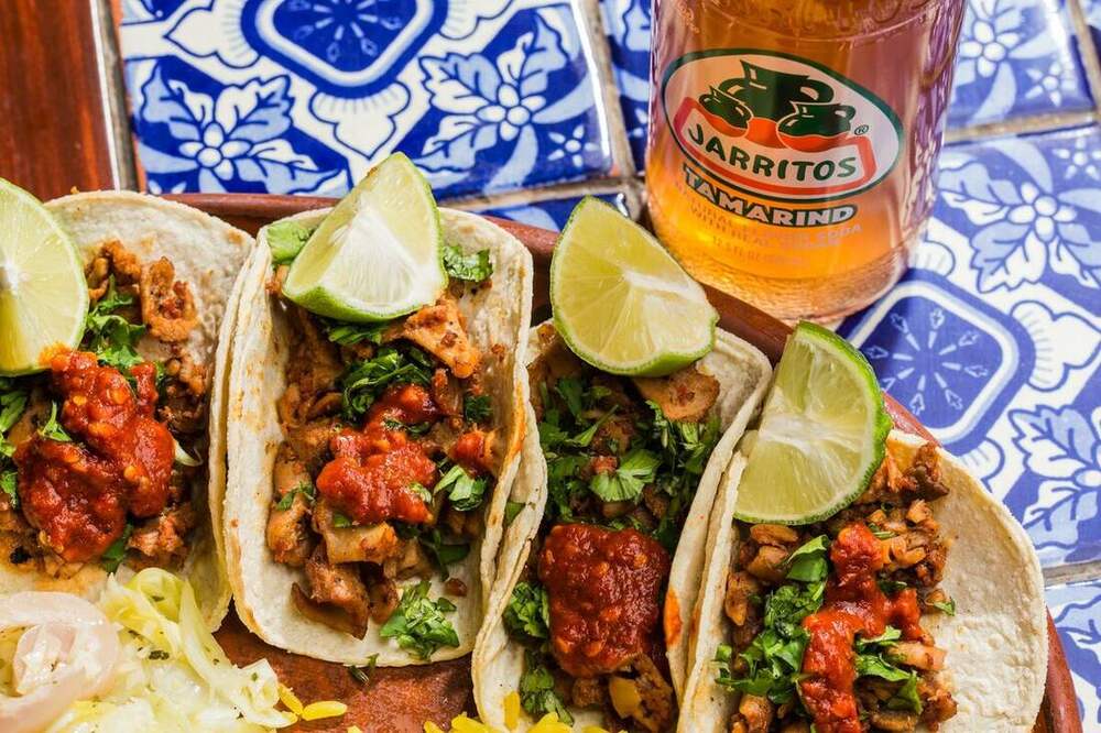 Tacos mexicains colorés servis avec citron vert et coriandre fraîche